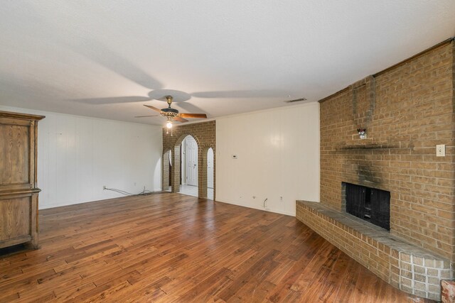 836 Springdale Rd, Bedford, TX 76021 - unfurnished living room featuring ceiling fan, a fireplace, arched walkways, wood finished floors, and visible vents