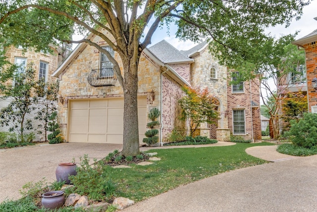 view of front of home featuring a garage, a front yard, stone siding, a shingled roof, and concrete driveway
