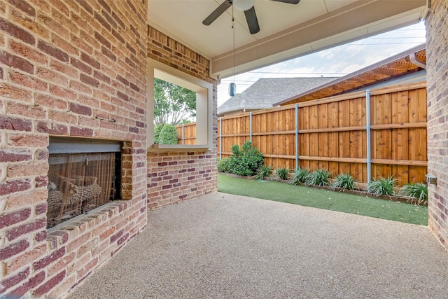 view of patio / terrace featuring ceiling fan, fence, and an outdoor brick fireplace