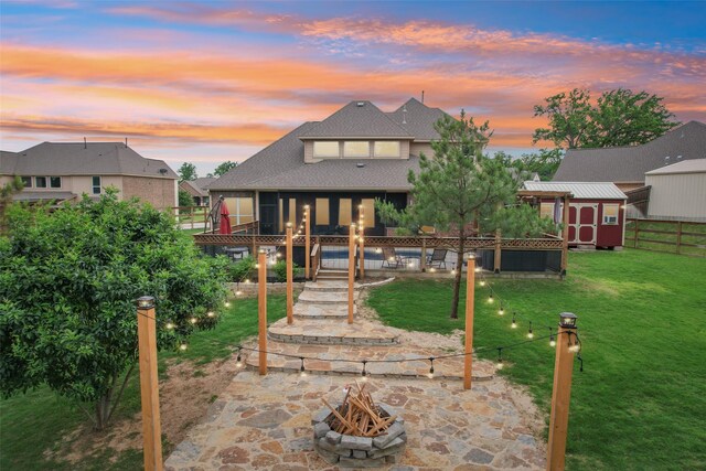 143 Dogwood Dr, Krugerville, TX 76227 - back of property at dusk featuring an outbuilding, fence, a shingled roof, a shed, and a yard