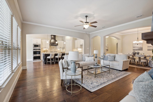 living area featuring visible vents, crown molding, arched walkways, ceiling fan with notable chandelier, and dark wood-type flooring