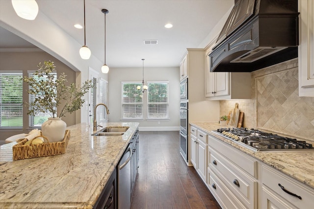 kitchen featuring visible vents, a sink, premium range hood, light stone counters, and stainless steel appliances
