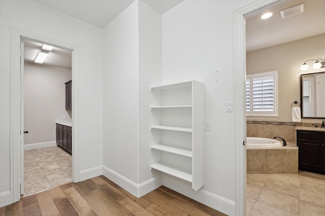 full bath with vanity, wood finished floors, a bath, and visible vents