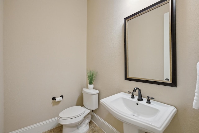 bathroom featuring toilet, baseboards, a sink, and tile patterned floors
