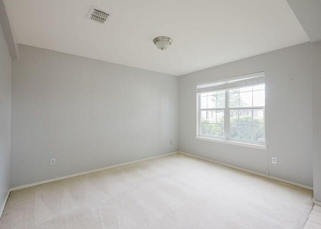 empty room with light colored carpet, baseboards, and visible vents