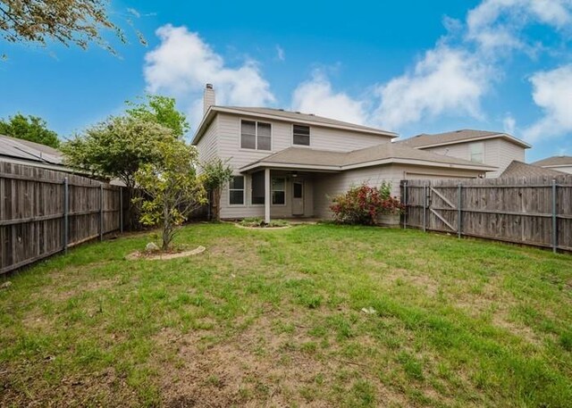 rear view of property with a fenced backyard, a yard, and a chimney
