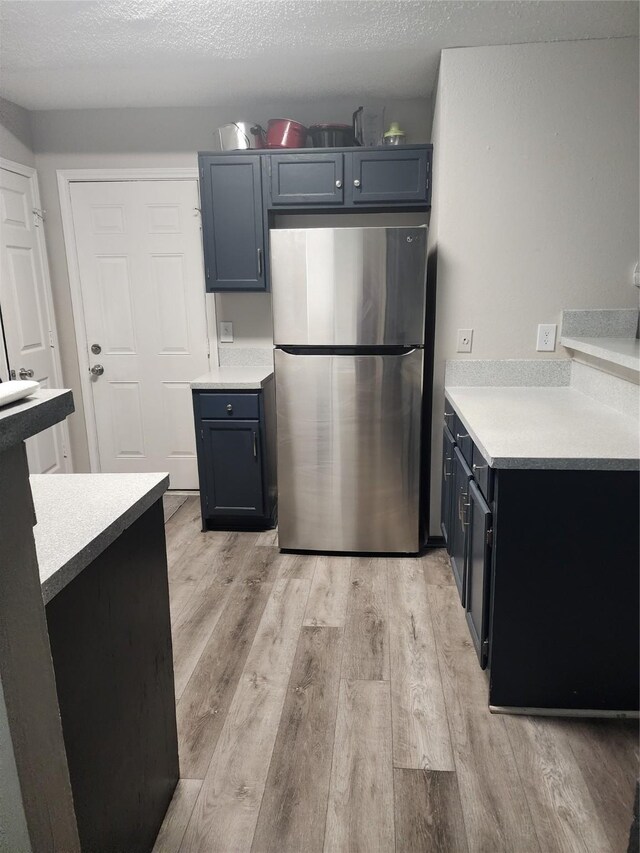 kitchen with light wood-type flooring, freestanding refrigerator, and light countertops