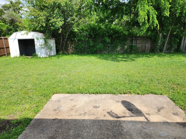 view of yard with an outdoor structure, a fenced backyard, and a shed