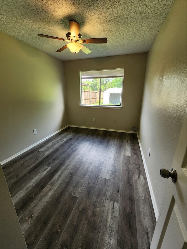 unfurnished room featuring dark wood-style flooring, a ceiling fan, baseboards, and a textured ceiling