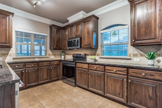 kitchen featuring a peninsula, decorative backsplash, stainless steel appliances, and dark stone countertops