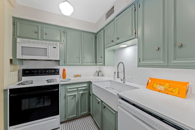 kitchen with visible vents, a sink, light countertops, green cabinetry, and white appliances