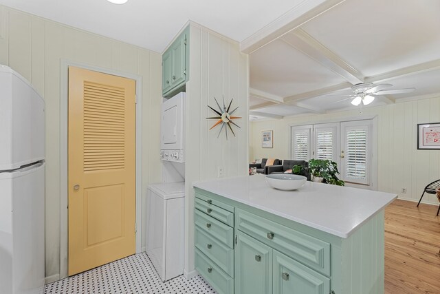 kitchen featuring freestanding refrigerator, stacked washing maching and dryer, a peninsula, and green cabinets