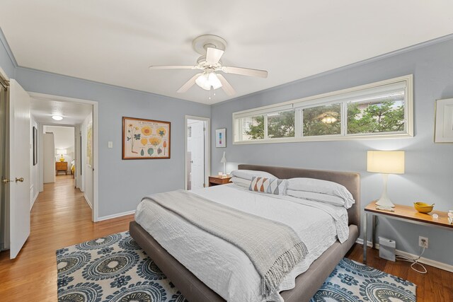 bedroom with a ceiling fan, baseboards, and light wood-style flooring