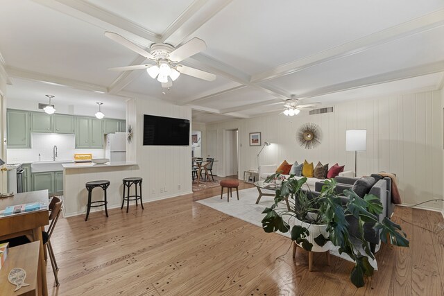 living room featuring ceiling fan, coffered ceiling, light wood finished floors, and visible vents