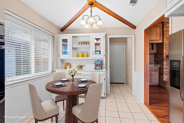 dining room with visible vents, wainscoting, a chandelier, vaulted ceiling with beams, and light tile patterned flooring