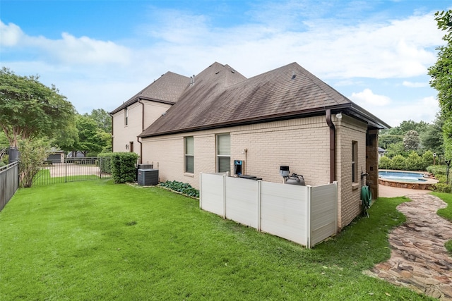 view of home's exterior with roof with shingles, brick siding, a lawn, a hot tub, and central air condition unit
