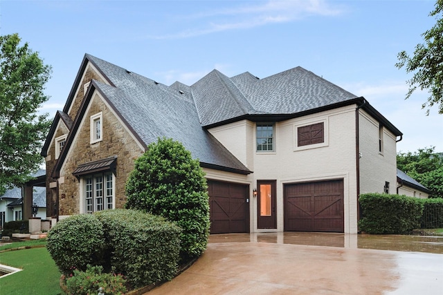 view of front of home featuring an attached garage, driveway, and stone siding