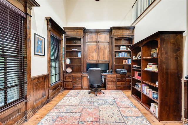 office space featuring a wainscoted wall, built in study area, and light wood-style floors