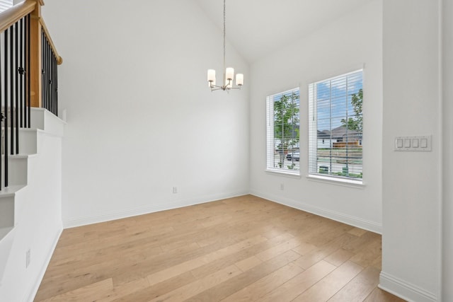 interior space with a high ceiling, baseboards, ceiling fan with notable chandelier, and wood finished floors