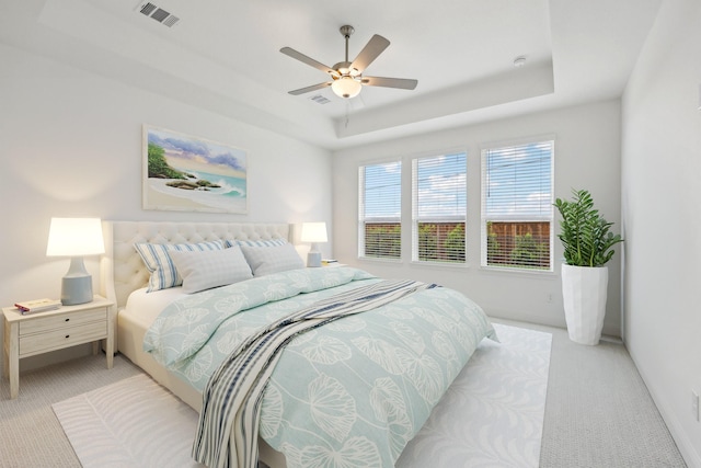 carpeted bedroom with visible vents, a ceiling fan, a raised ceiling, and baseboards