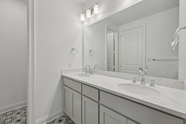full bath featuring double vanity, a sink, and baseboards