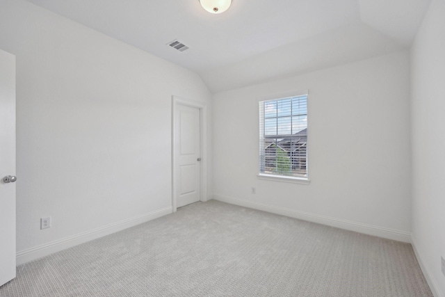 spare room with light colored carpet, baseboards, lofted ceiling, and visible vents