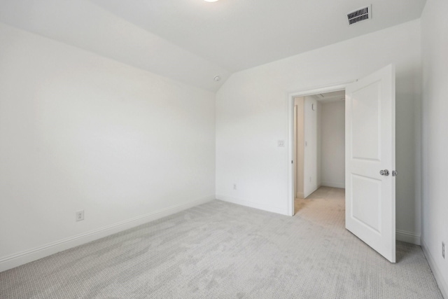 spare room with light colored carpet, baseboards, lofted ceiling, and visible vents
