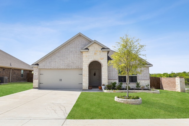 french country style house featuring a front lawn, brick siding, a garage, stone siding, and concrete driveway