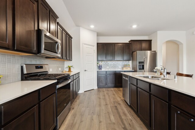 kitchen with a sink, appliances with stainless steel finishes, dark brown cabinets, and light countertops