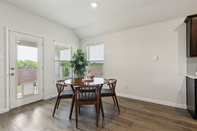 dining room with baseboards, vaulted ceiling, and dark wood-style floors