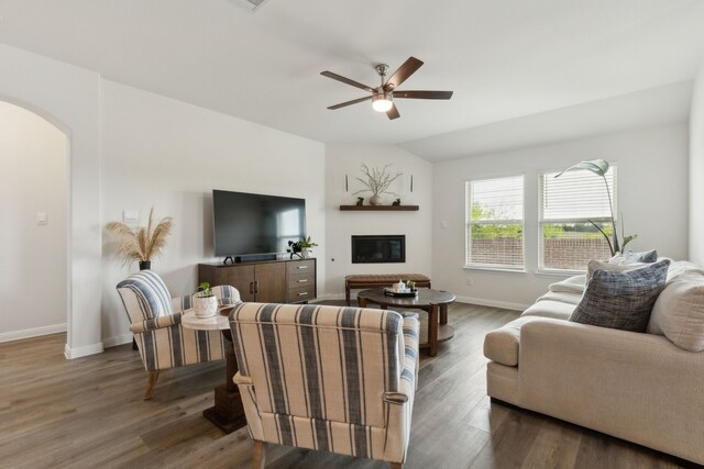 living room with a ceiling fan, a glass covered fireplace, wood finished floors, baseboards, and arched walkways