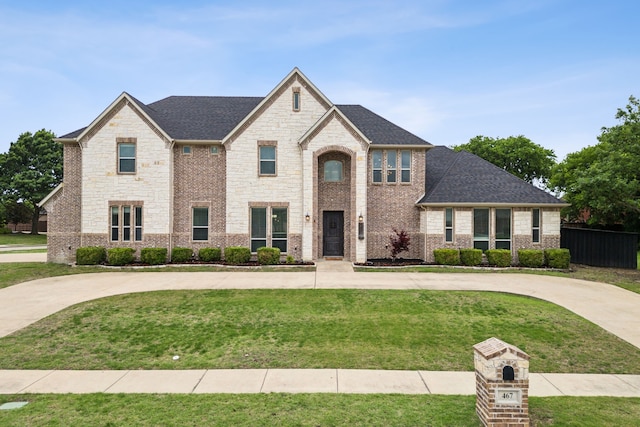 view of front of home featuring curved driveway, fence, stone siding, and a front yard