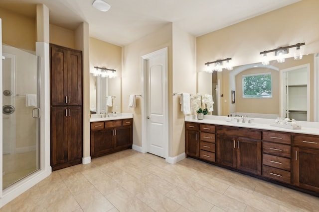bathroom with a sink, a closet, a shower stall, and two vanities