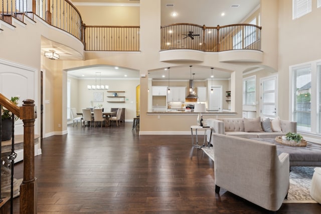 living room featuring arched walkways, a high ceiling, ornamental molding, and dark wood-type flooring