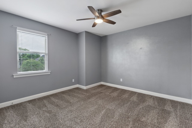 unfurnished room with baseboards, a ceiling fan, and dark carpet