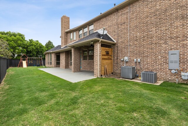 back of property featuring brick siding, a fenced backyard, a chimney, a patio area, and a playground