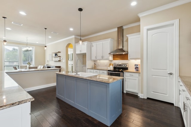 kitchen with wall chimney exhaust hood, arched walkways, stainless steel electric stove, white cabinets, and a sink
