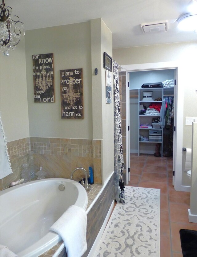 full bath with a bath, a notable chandelier, a spacious closet, and tile patterned flooring