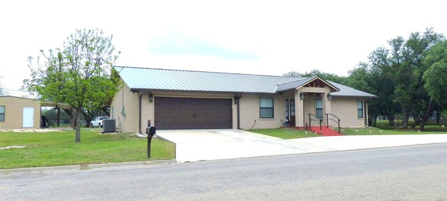 single story home with driveway, metal roof, a front yard, a garage, and stucco siding