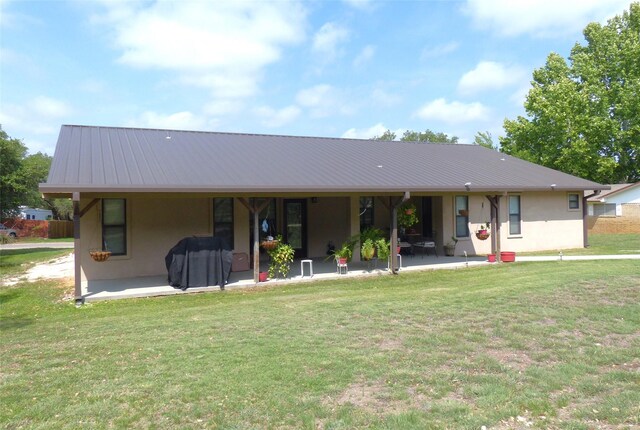 view of front of property with stucco siding, a patio area, and metal roof