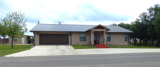 single story home with driveway, metal roof, a front yard, an attached garage, and stucco siding