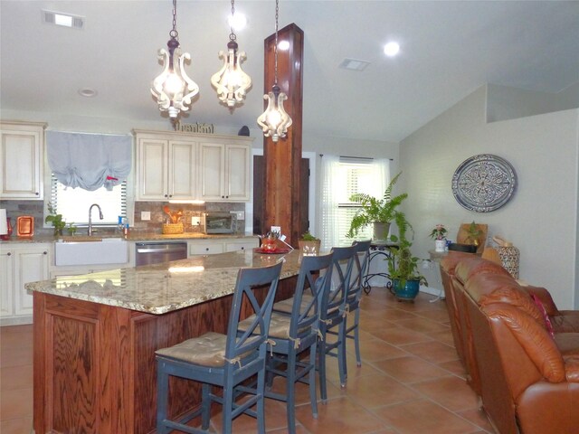 kitchen featuring cream cabinetry, lofted ceiling, dishwasher, and a healthy amount of sunlight