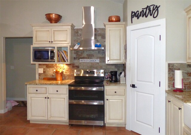 kitchen with wall chimney range hood, stainless steel appliances, light tile patterned floors, and tasteful backsplash