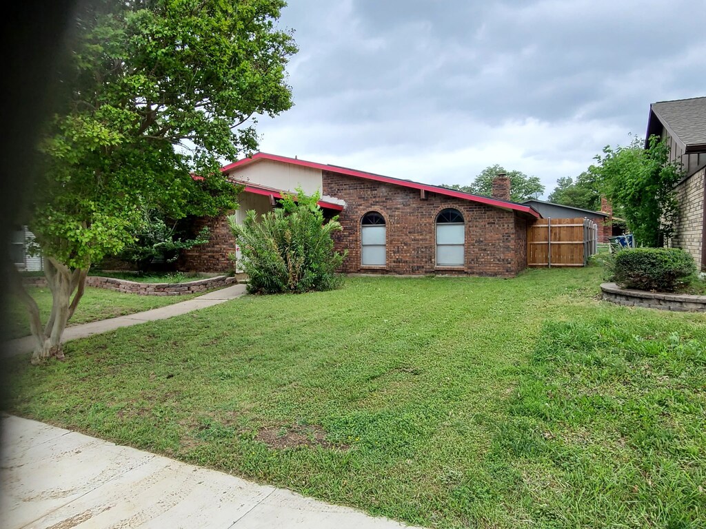 view of front of property with fence, a chimney, a front yard, and brick siding