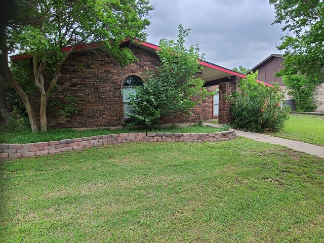 view of front facade with brick siding and a front yard