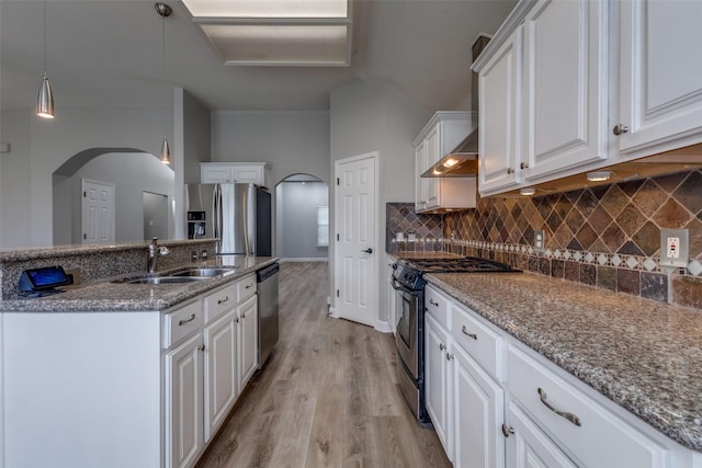 kitchen featuring white cabinets, tasteful backsplash, a sink, light wood-style flooring, and appliances with stainless steel finishes