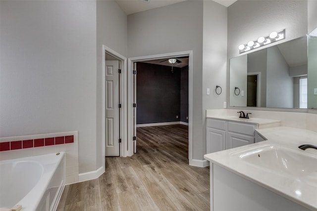 bathroom featuring baseboards, wood finished floors, a garden tub, and vanity