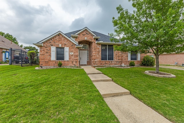 ranch-style house featuring brick siding, a front yard, and roof with shingles