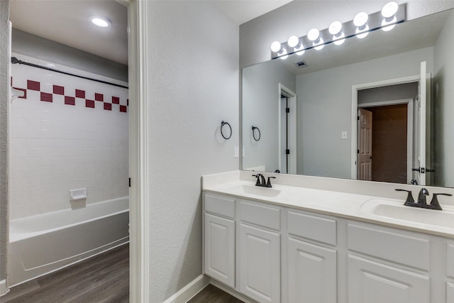 bathroom featuring double vanity, a sink, shower / tub combination, and wood finished floors