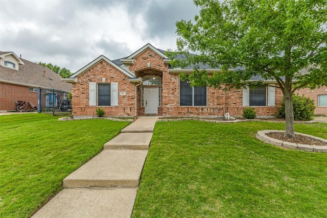single story home featuring fence, a front yard, and brick siding
